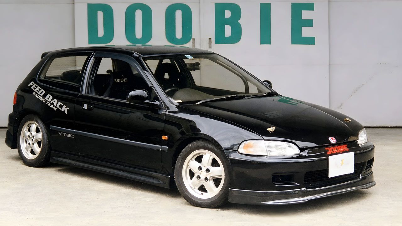 An EG6 Civic outside the DOOBIE workshop in Daito, Osaka, the company name painted in green on the wall behind